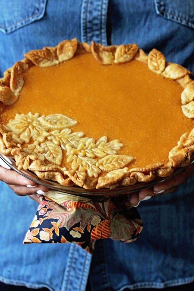 Hands holding decorated Sweet Potato Chess Pie ready to serve 
