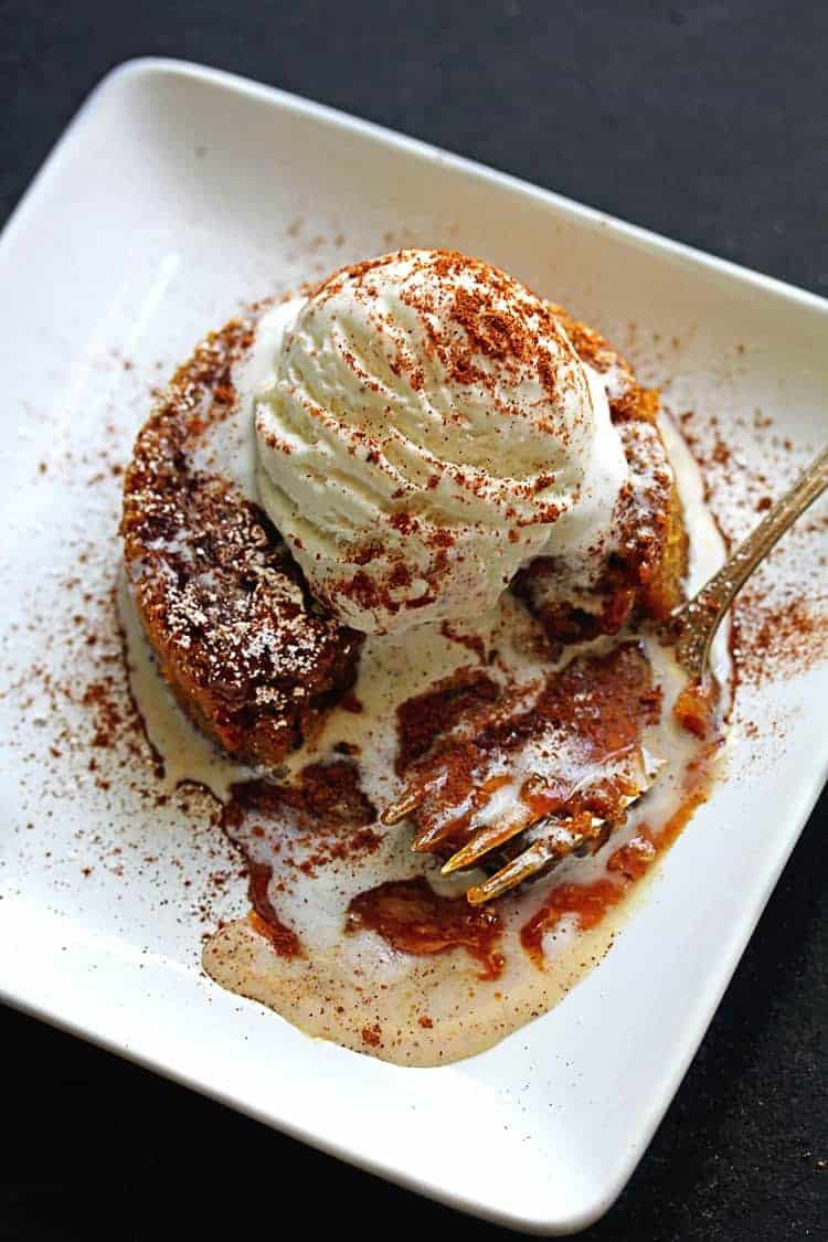 An overhead shot of a Pumpkin Caramel Lava Cake recipe with caramel and chocolate oozing from inside with vanilla ice cream melting