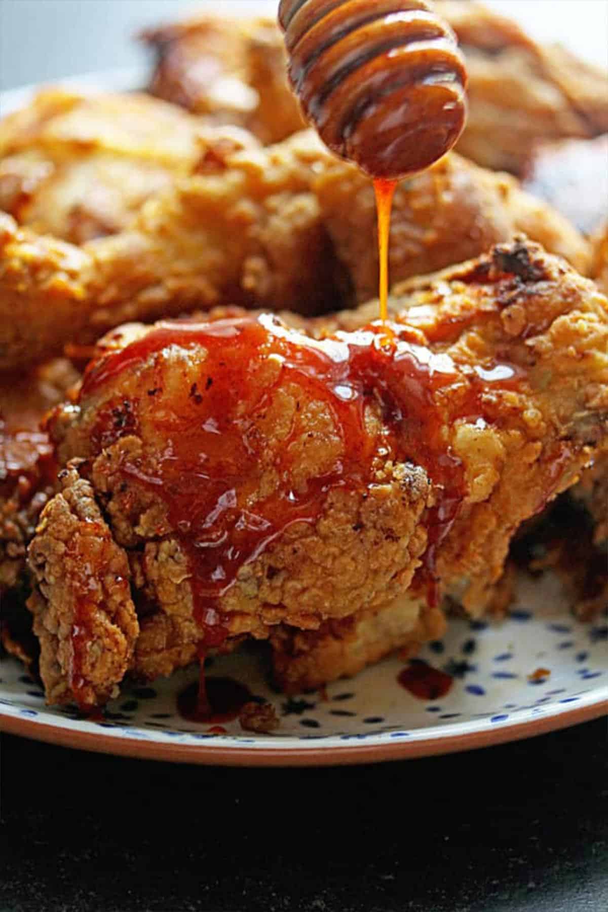 Cayenne spiced honey glaze is drizzled over buttermilk fried chicken recipe ready to serve.