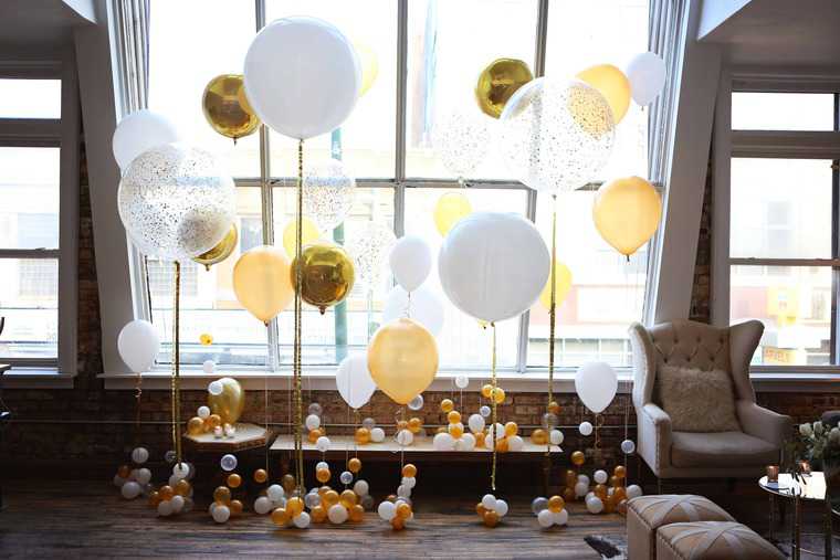 Several balloons hanging a strings in front of a window