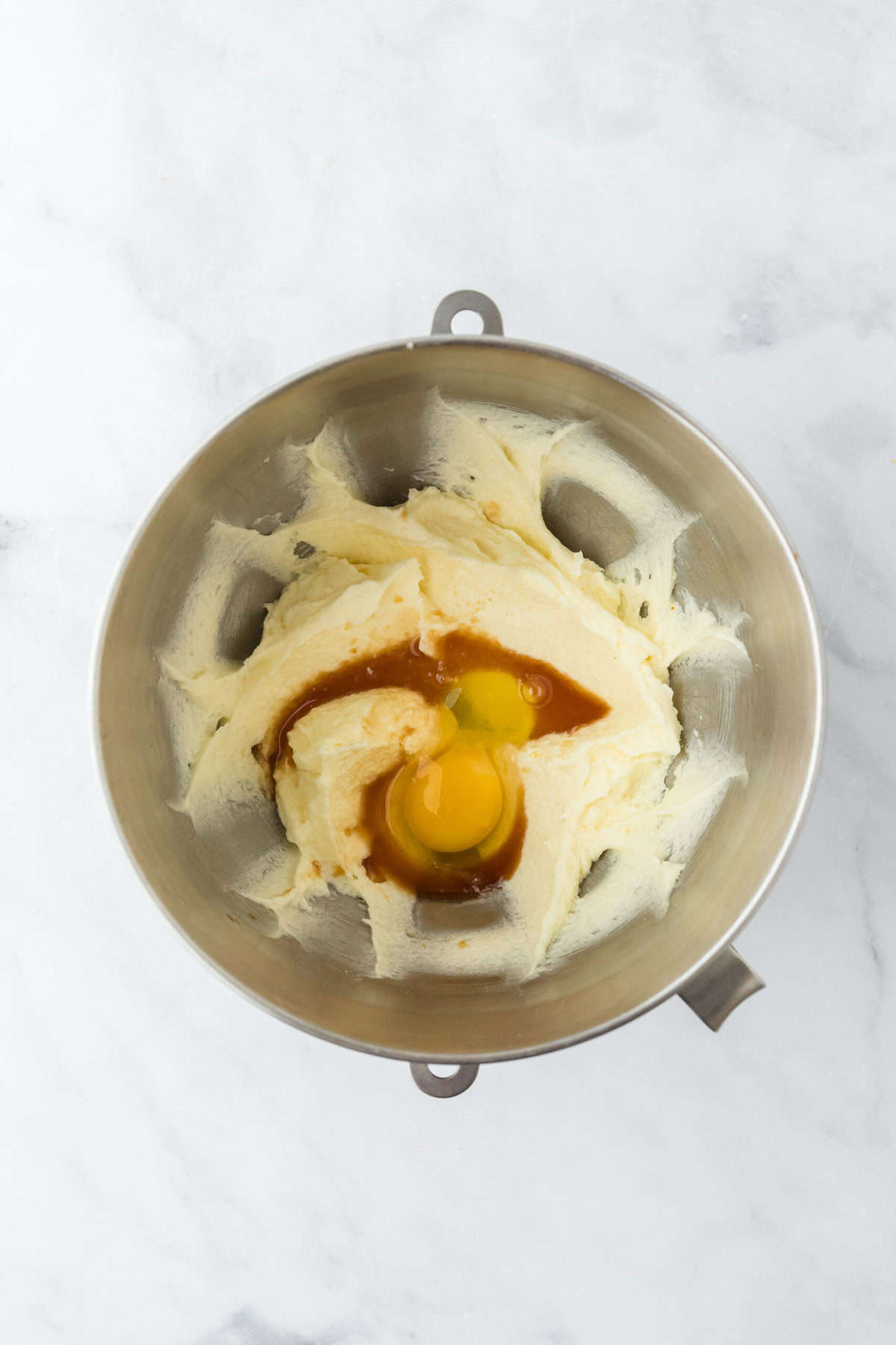 Eggs added to a cookie batter in stand mixer on white countertop