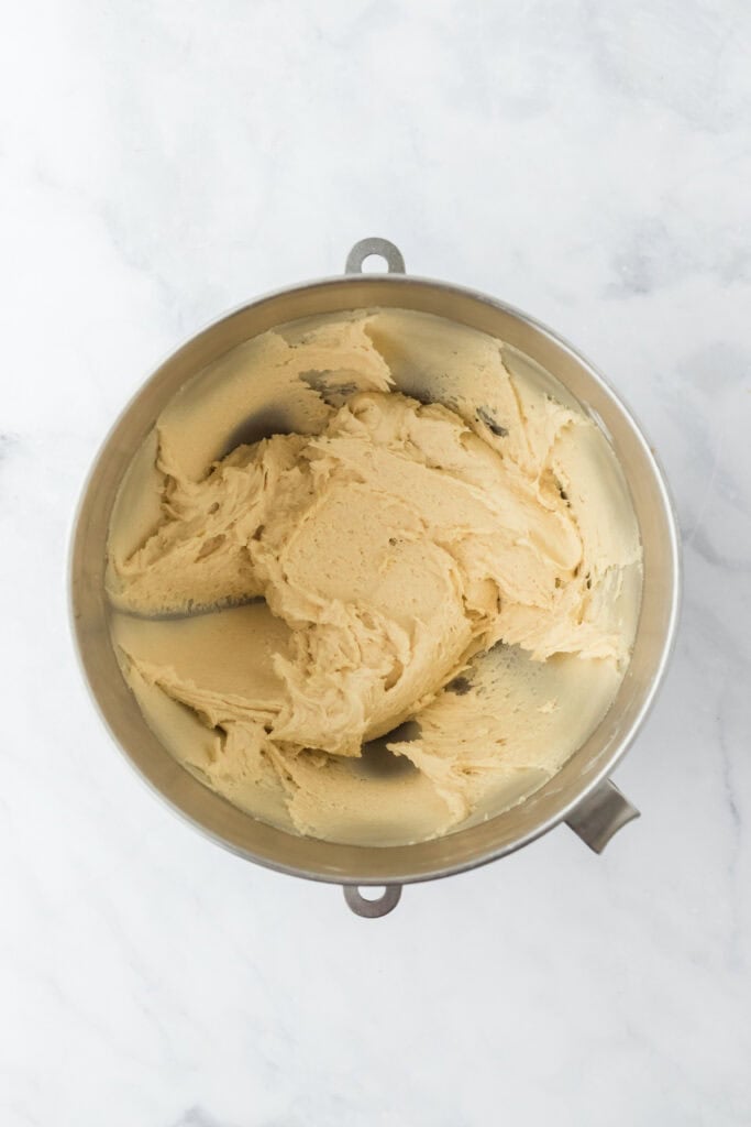 Finished ricotta cookie recipe batter in a stand mixer bowl on white background