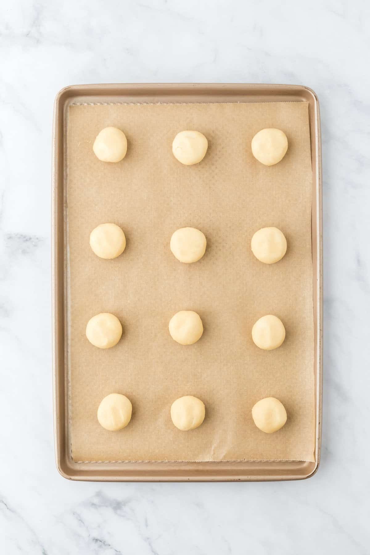 Italian ricotta cookie dough on a parchment lined baking sheet on white countertop