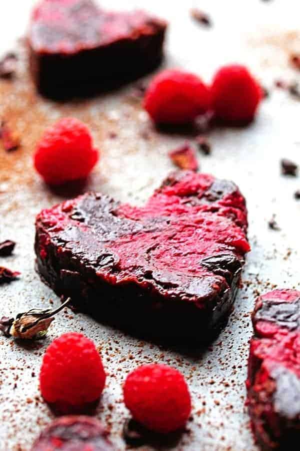 A close up of raspberry swirled brownies with raspberry garnishes