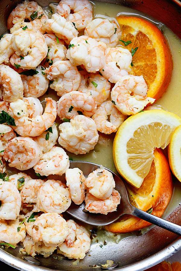 Close up of Lemon Shrimp Recipe with orange slices and a spoon in it