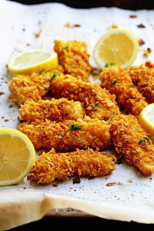 Crispy Baked Fish Sticks on a piece of parchment paper and lemon slices