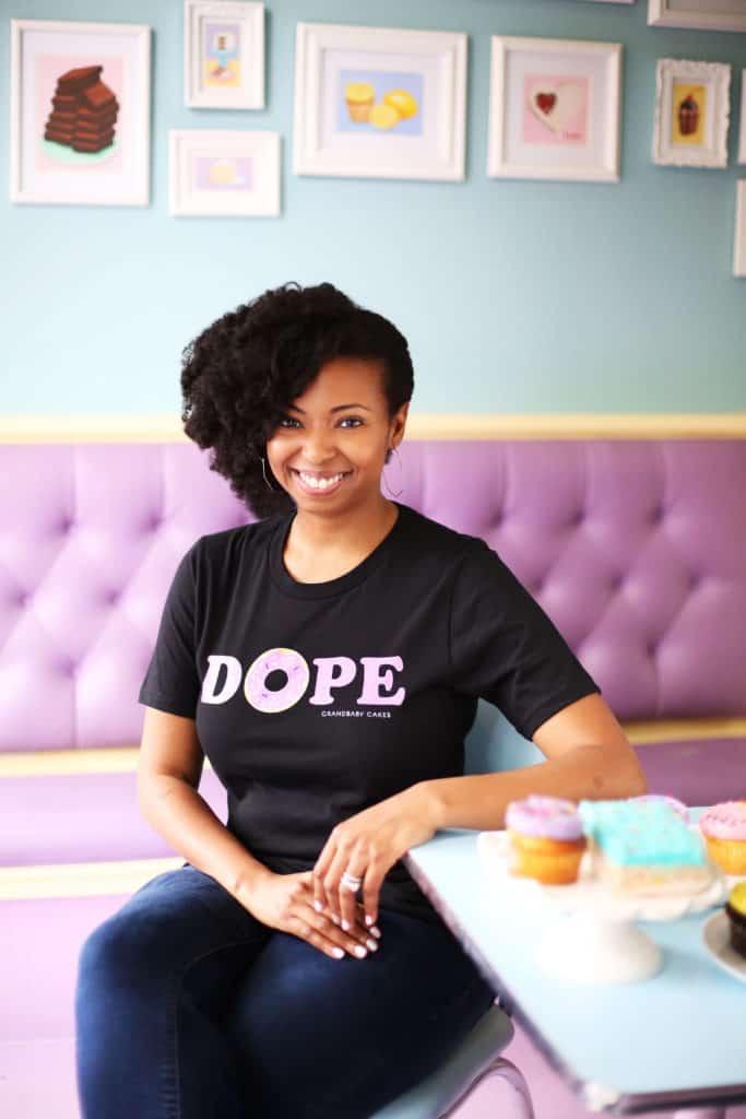 A seated Jocelyn wearing a black t-shirt with the word "Dope" with the O as a donut