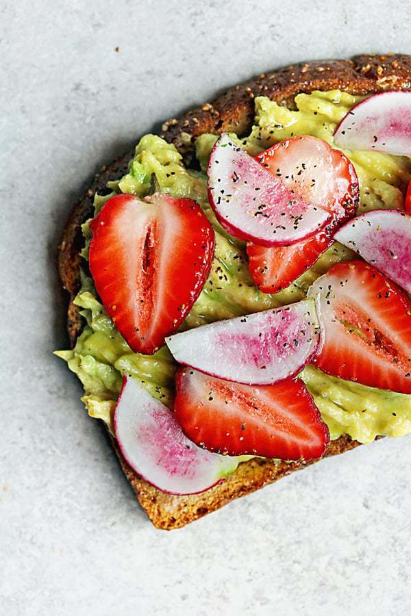 Learn how to make avocado toast; this photo depicts avocado toast topped with strawberries.