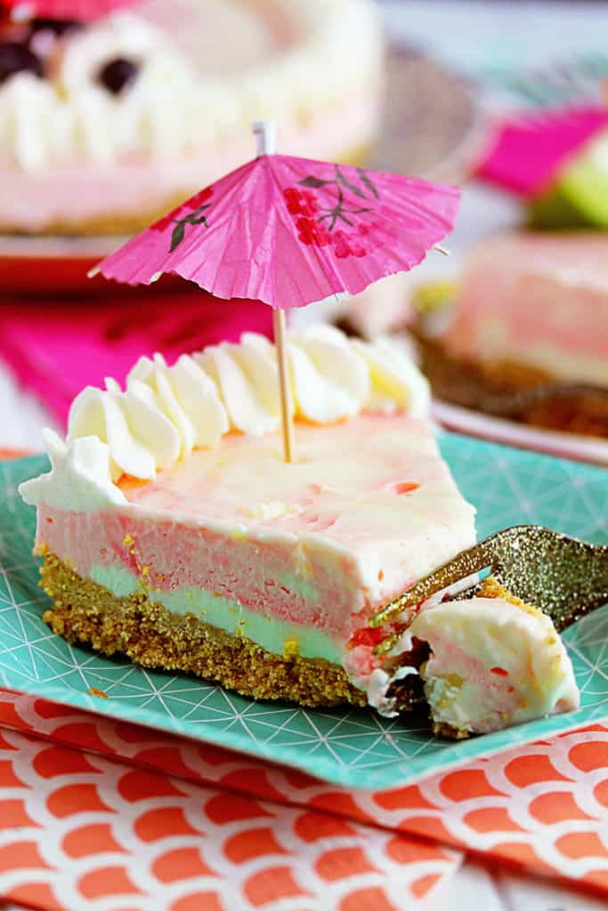 Close up of a piece of Bacardi Miami Vice No Bake Cheesecake with a small drink umbrella on top