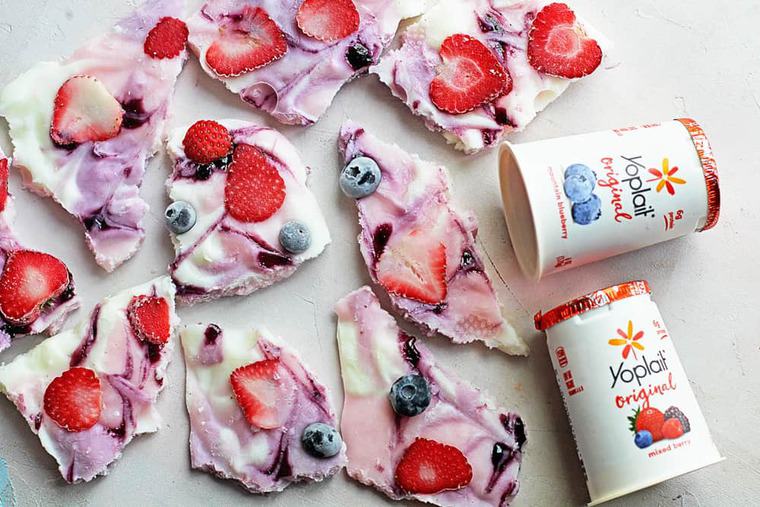 Overhead shot of Frozen Yogurt Bark topped with strawberries, raspberries and blueberries and a couple of containers of yoplait yogurt