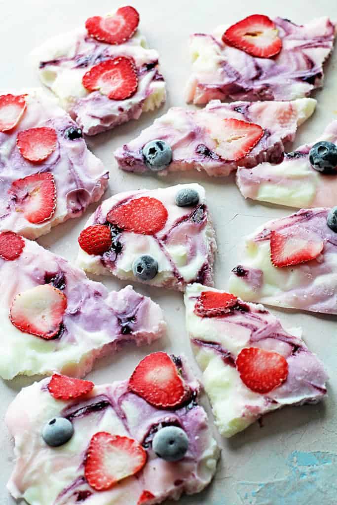 Several pieces of Frozen Yogurt Bark topped with strawberries, raspberries and blueberries