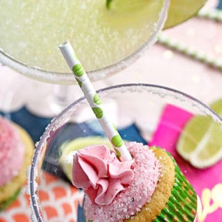 A margarita cupcake inside a margarita glass next to a glass of frozen margarita with lime