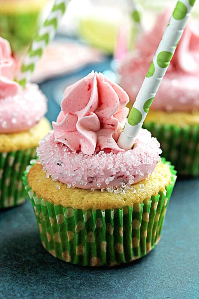 A grouping of margarita cupcakes with straws sticking out ready to enjoy