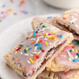 Homemade Pop Tarts Recipe layered on a white plate with sprinkles on them and in the gray background