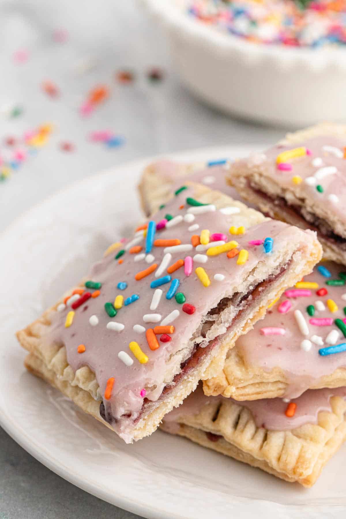 A homemade pop tart on the table cut in half to show the inside and stacked on other poptarts on the plate.