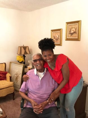 Jocelyn Delk Adams posing for a photo with her Big Daddy, who is seated in a chair