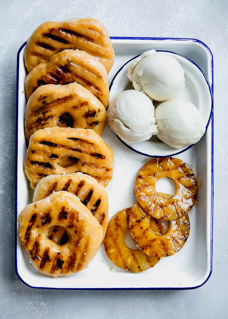 Overhead of Grilled Pineapple slices and grilled donuts with vanilla ice cream on a white tray 