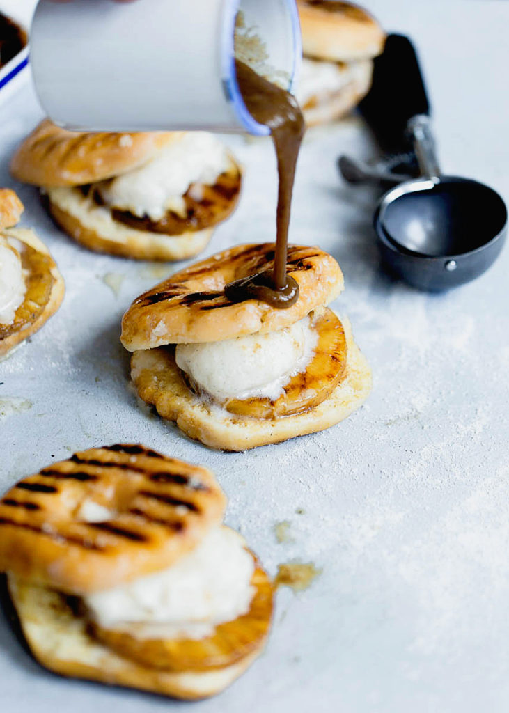 Sauce being poured over grilled pineapples, ice cream and grilled donuts