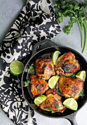 Overhead shot of crispy skillet baked garlic chicken contained in a cast iron skillet with lime 