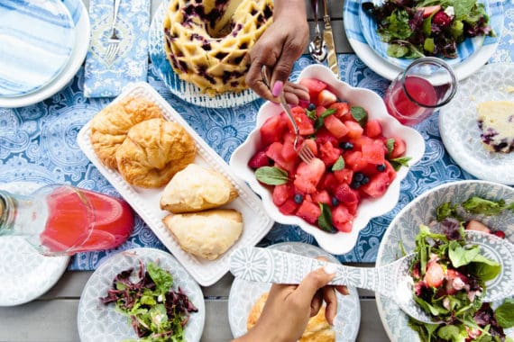 Overhead shot of foods on the picnic table including salad, fruit and a blueberry orange pound cake
