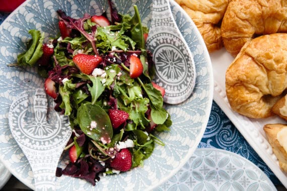 Overhead of a Home Goods bowl full of salad and croissants