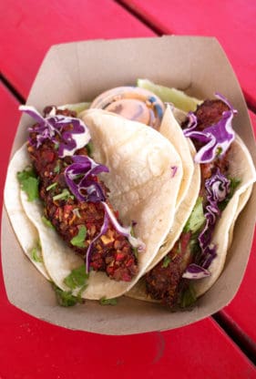 A couple of fish tacos from Trudy's Tex Mex on a red bench in Austin, TX