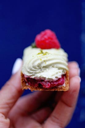 A half eaten eclair topped with whipped cream and a raspberry from L’Éclair de Génie