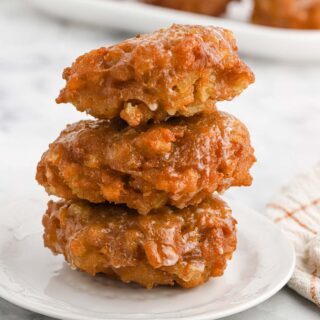 A stack of three apple fritters on a plate.