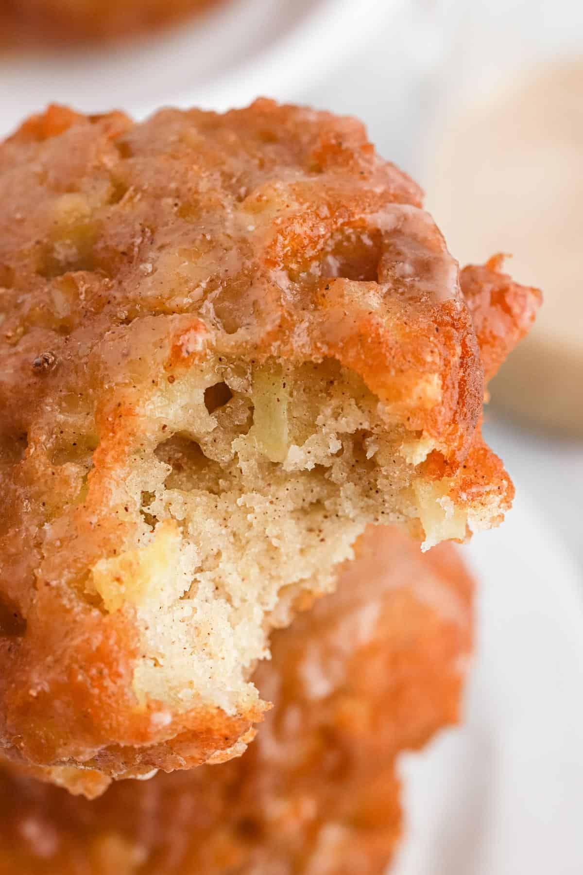 A closeup of an apple fritter with a bite missing.