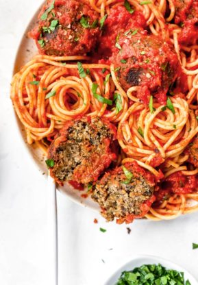 A close up of spaghetti and meatballs with parsley chopped and ready to serve