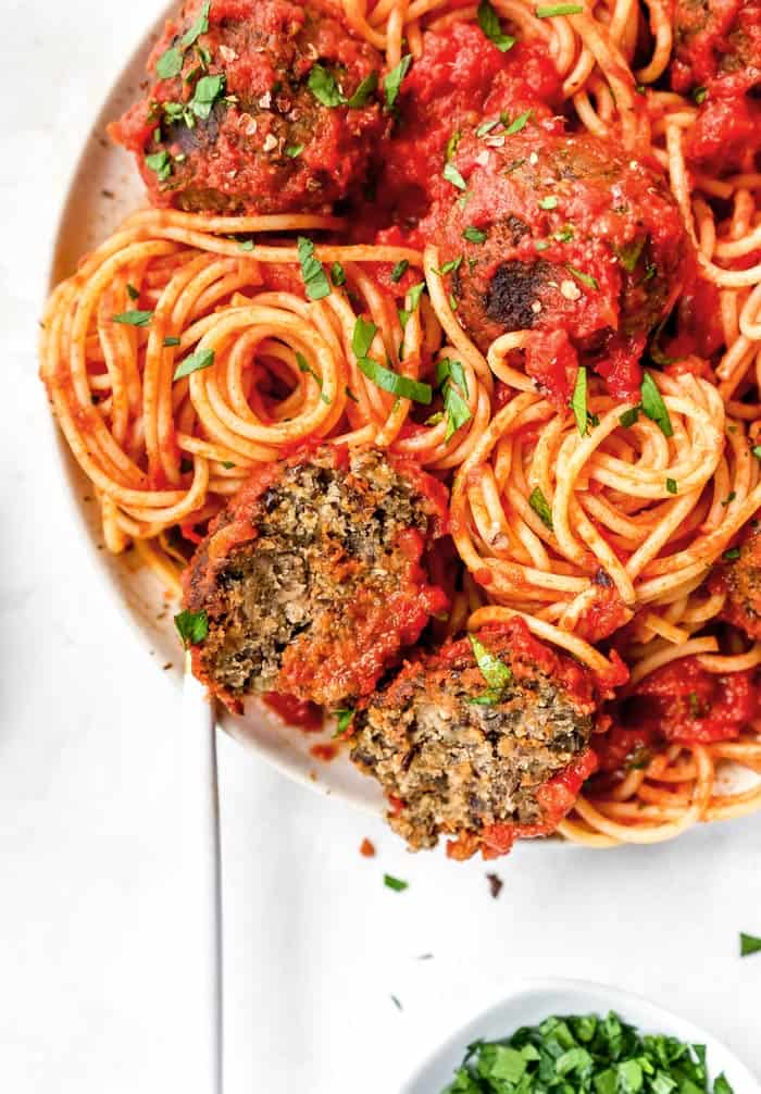 A close up of spaghetti and meatballs with parsley chopped and ready to serve