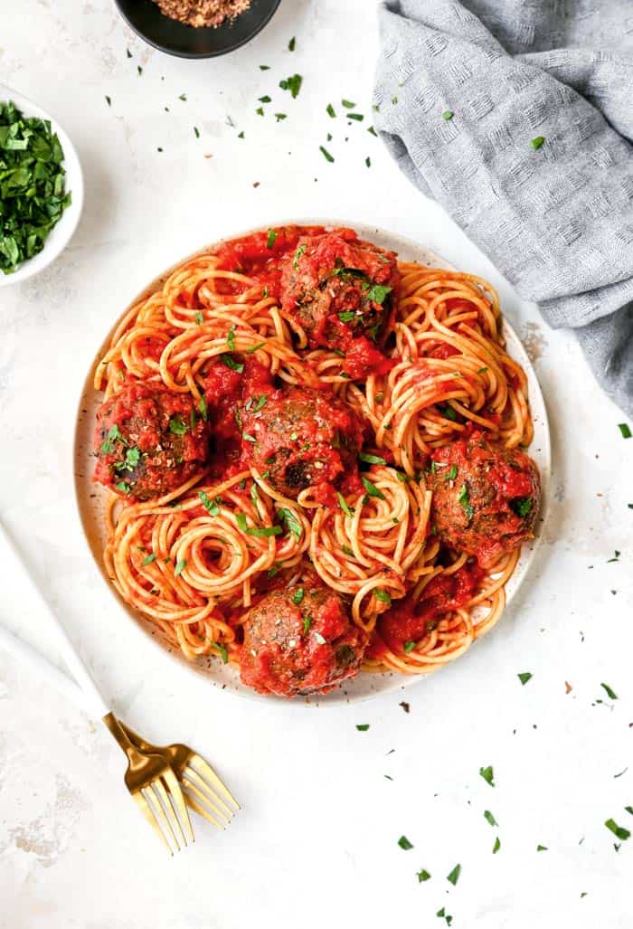 A white plate filled with vegetarian lentil meatballs over spaghetti ready to serve