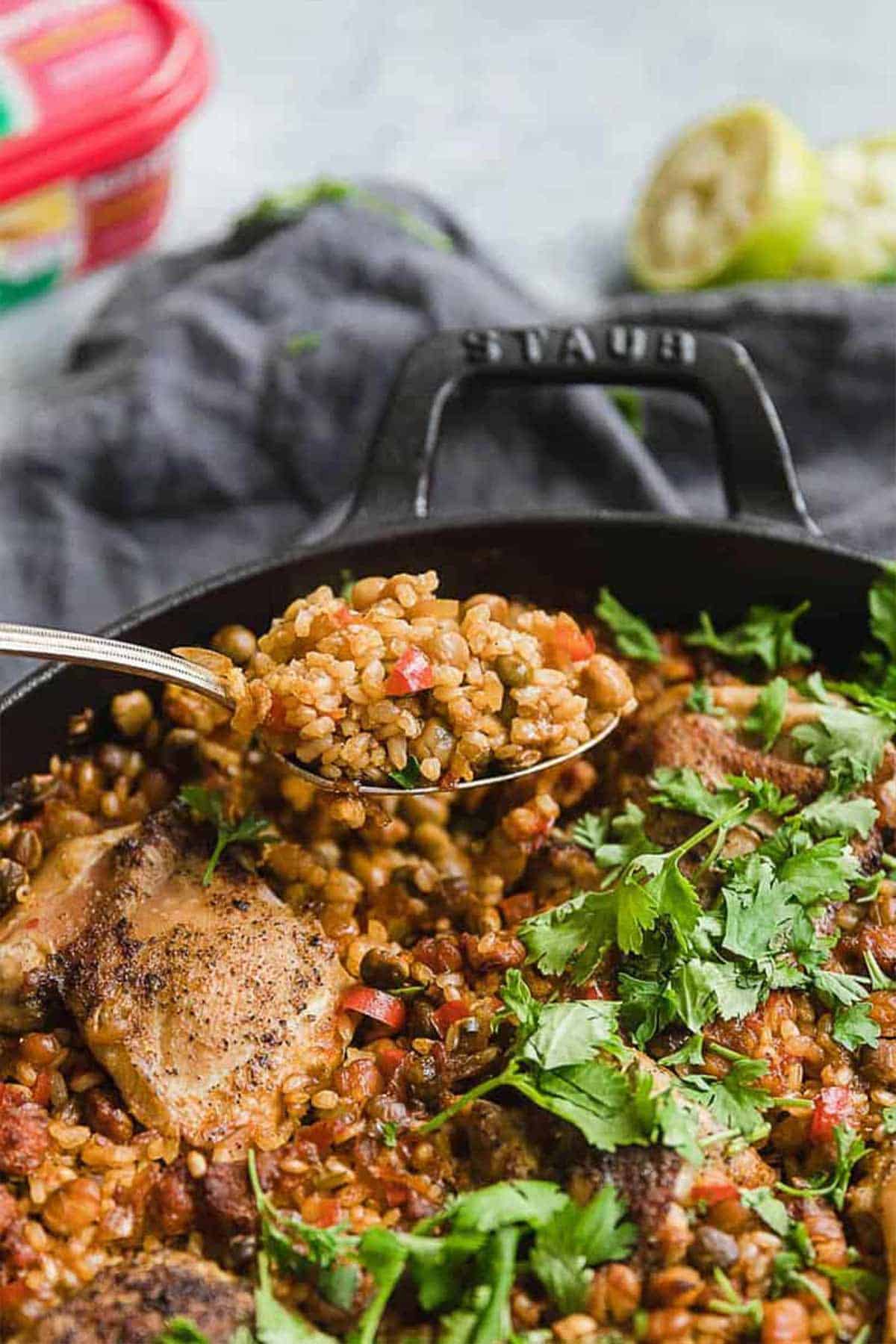 A fork holding up a bite of spanish chicken with rice over the pot.