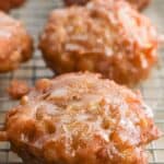 Glazed apple fritters on a wire rack.