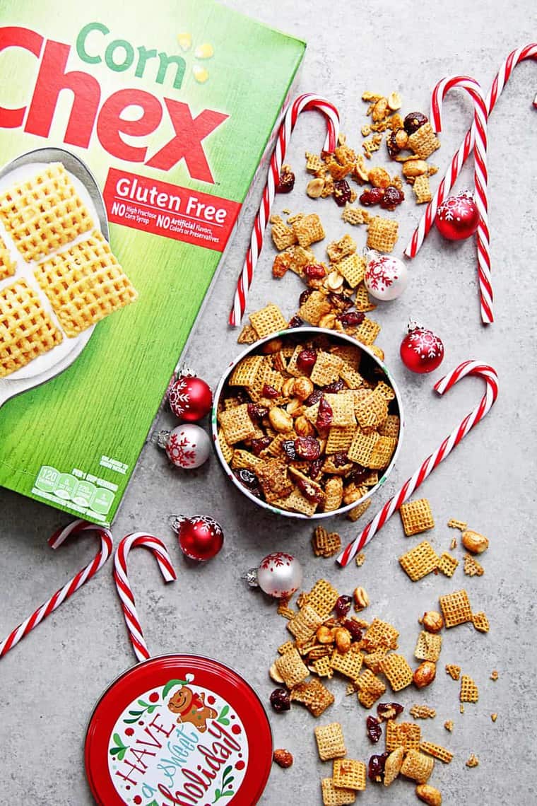 Cranberry Orange Chex Party Mix recipe in christmas container ready to give away with candy canes and ornaments in background