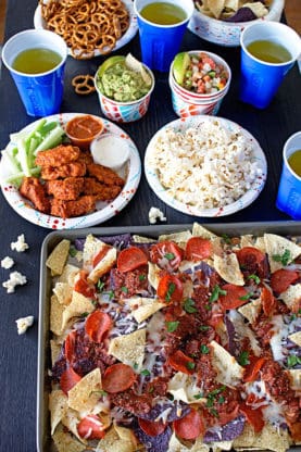 Overhead shot of Game Day Pizza Nachos next to hot wings, popcorn and other goodies