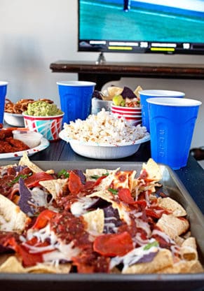 Game Day Pizza Nachos next to hot wings, popcorn and other goodies