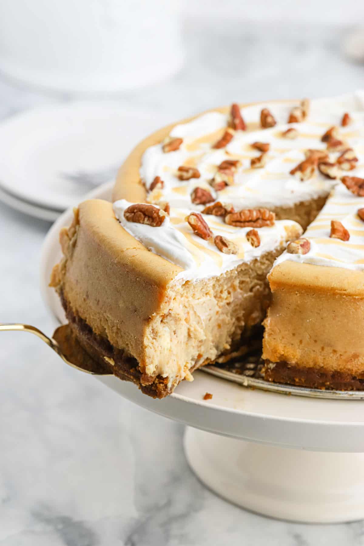 Spiced Sweet Potato Cheesecake Recipe on a white stand with slice being slid out