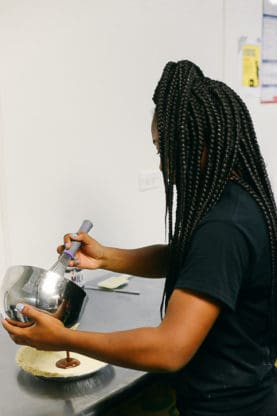 One student adding pie filling to a pie crust
