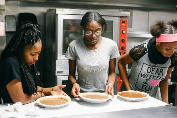 Three students looking at their pies as they wait their turn to put the pies in the oven