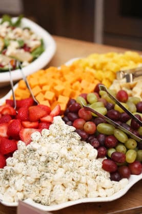 A white tray full of fruit and cheeses