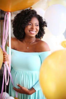 Jocelyn Delk Adams holding her baby bump and a balloon at her shower