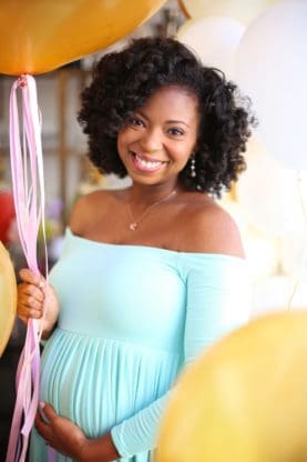 Jocelyn Delk Adams holding her baby bump and a balloon at her shower