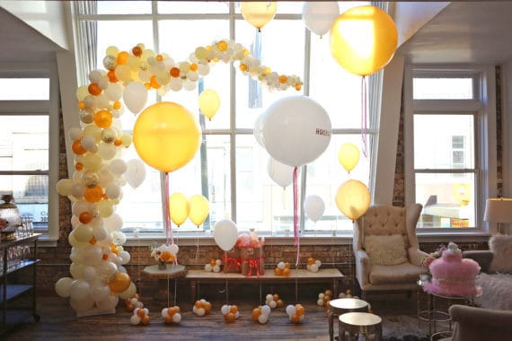 A beautiful arrangement of white and gold balloons in front of a window