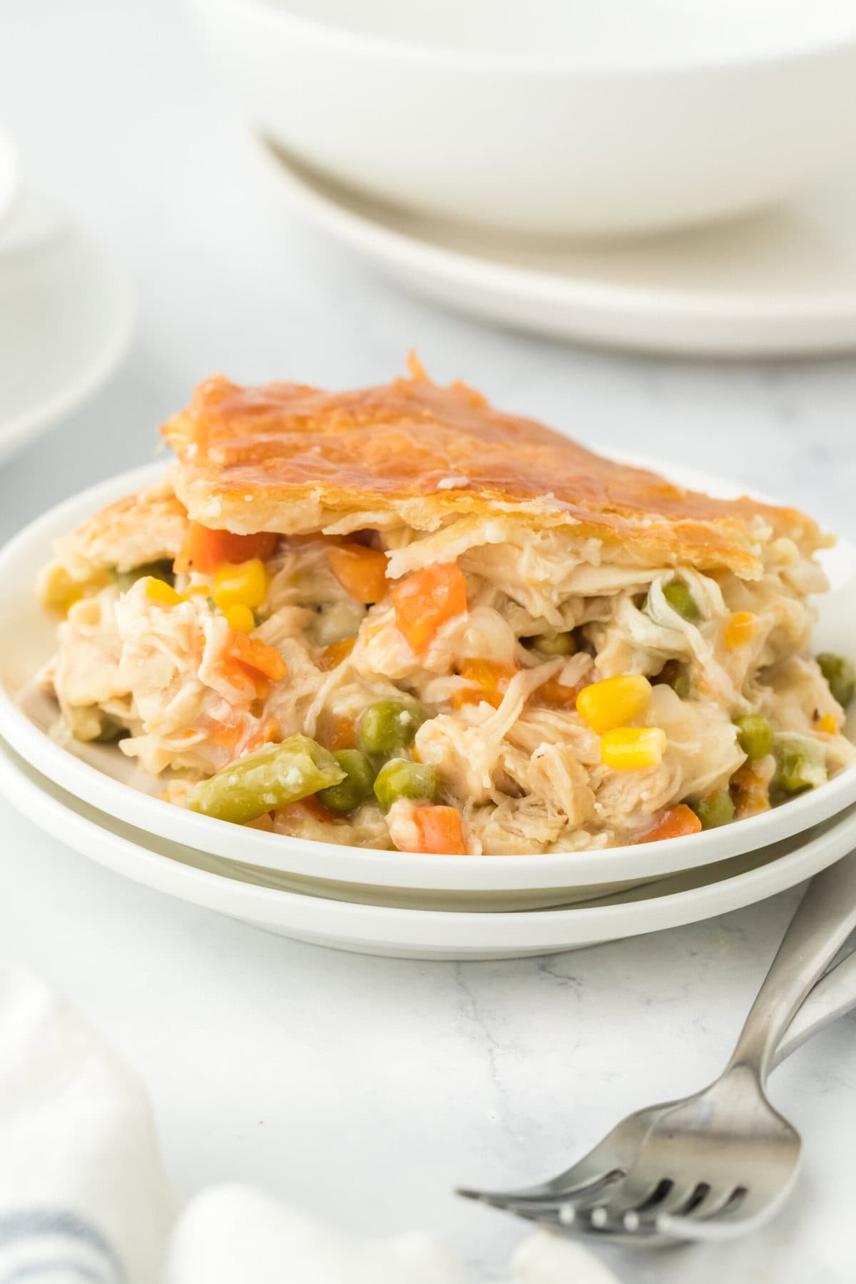 A slice of easy chicken pot pie on a white plate in a white background