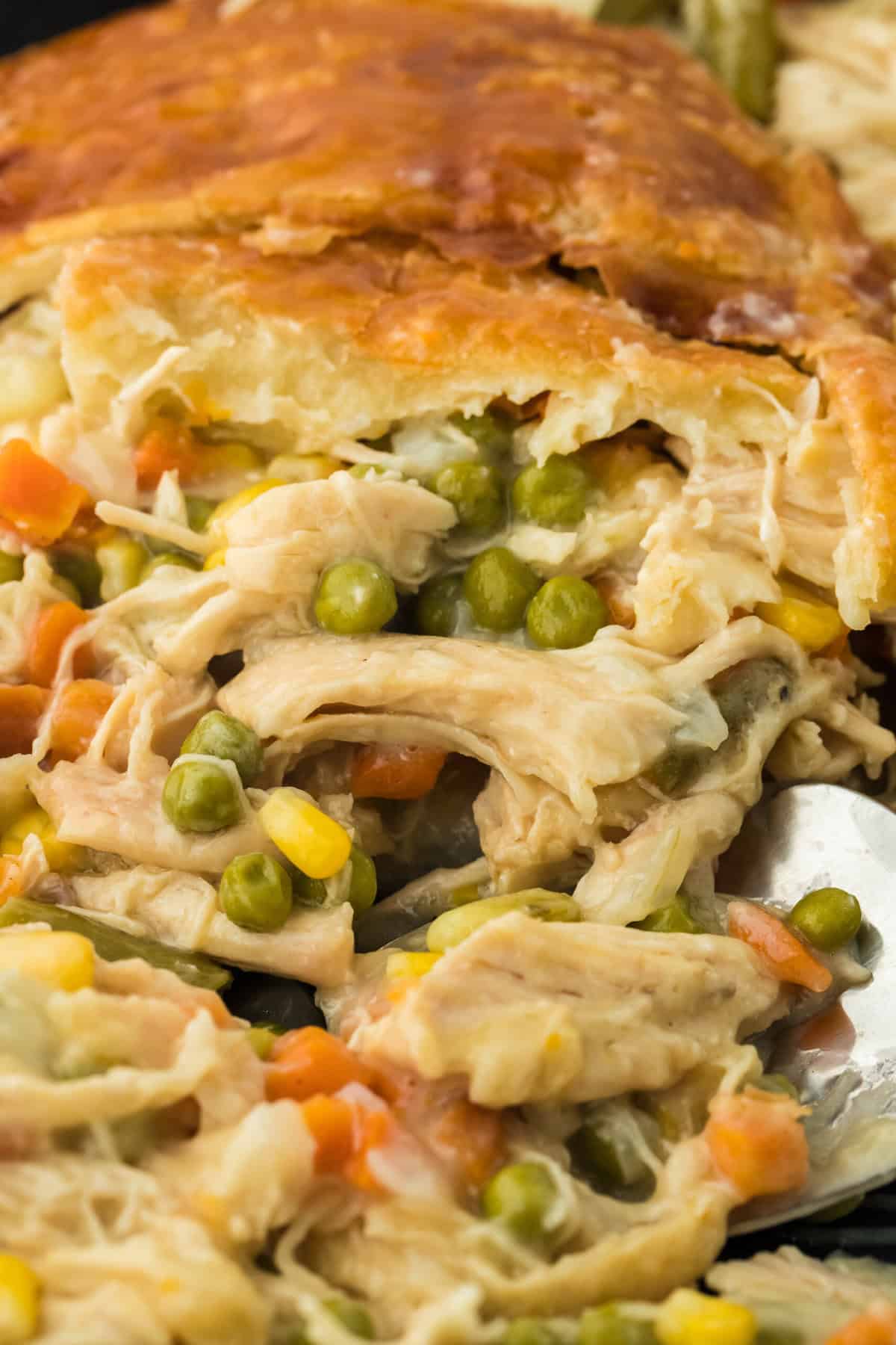 a close up of a homemade chicken pot pie being dug into with a spoon