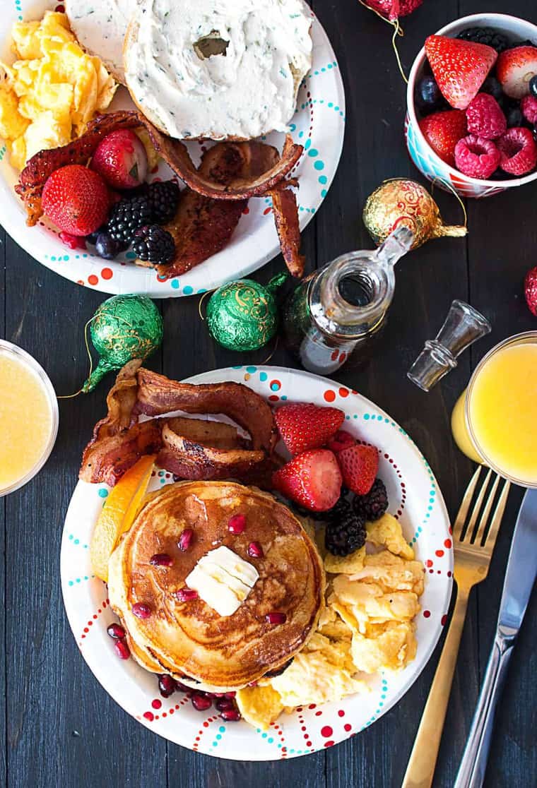 An overhead of Orange Ginger Pancakes, bacon, eggs, fruit and bagels ready to serve for a holiday brunch