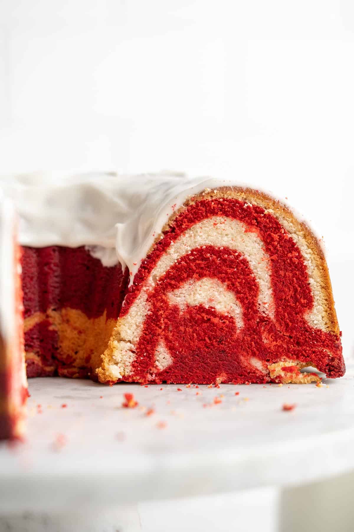 Red velvet swirl cake on a cake pedestal with a cross section cut to show inside of the cake.