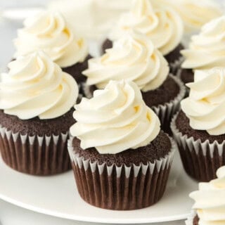Homemade chocolate cupcakes on a white plate with american frosting in a white background