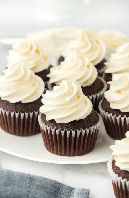 Homemade chocolate cupcakes on a white plate with american frosting in a white background